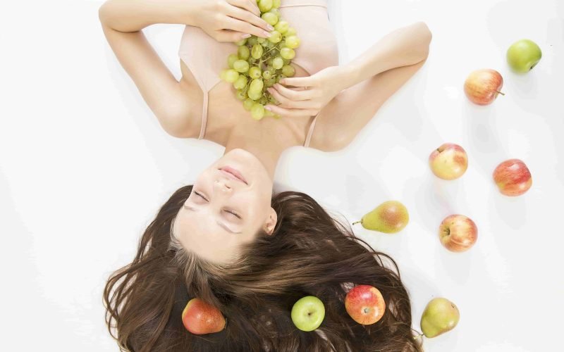 Woman with fruits exemplifying natural hair detox and cleansing for healthier hair.