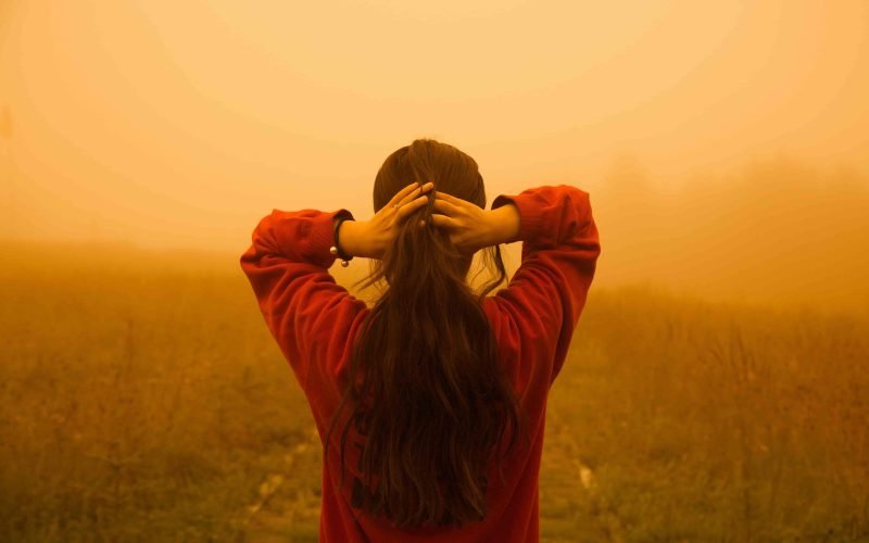 A woman with long hair standing in a field, illustrating how hair care boosts growth.