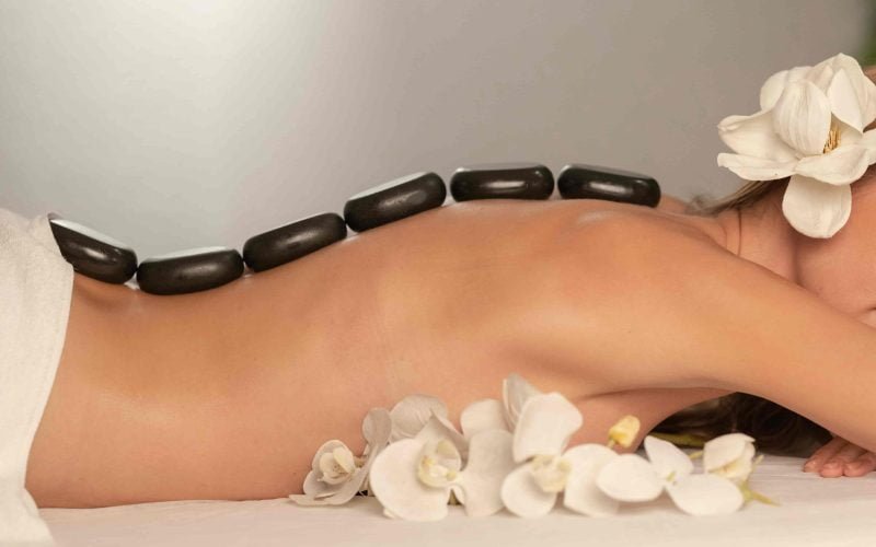 Relaxing spa treatment showcasing best routine for mature skin with hot stones and flowers.