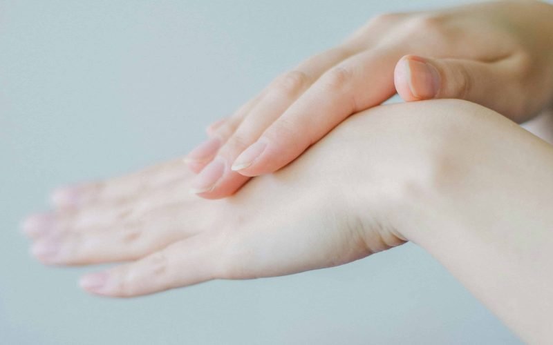 Hands applying moisturizer, illustrating a skin care routine for mixed skin types.