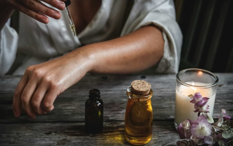 Woman applying essential oil on her arm, part of the best skin care routine for night rejuvenation.