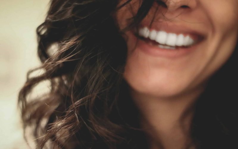 Close-up of a smiling woman with healthy skin, demonstrating the benefits of soothing face care routines.