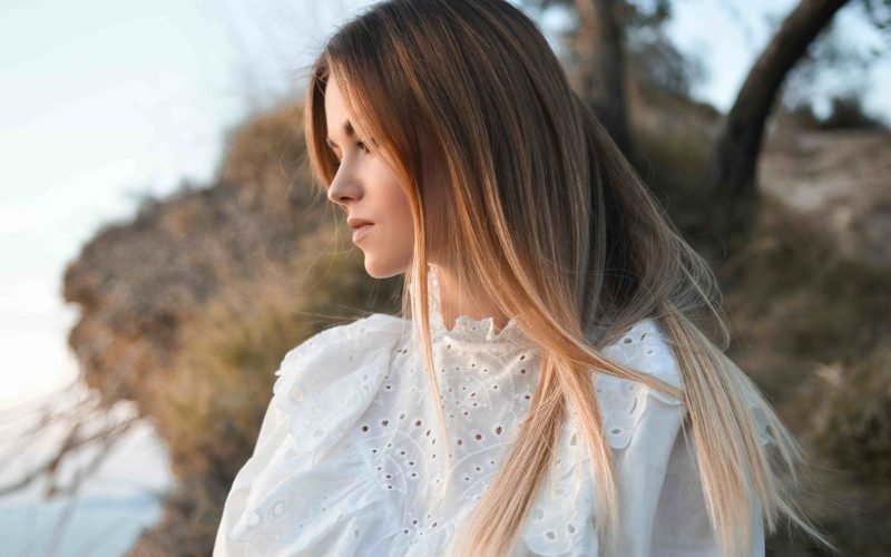 Woman with long hair outdoors, highlighting the importance of preventing acne from hair care